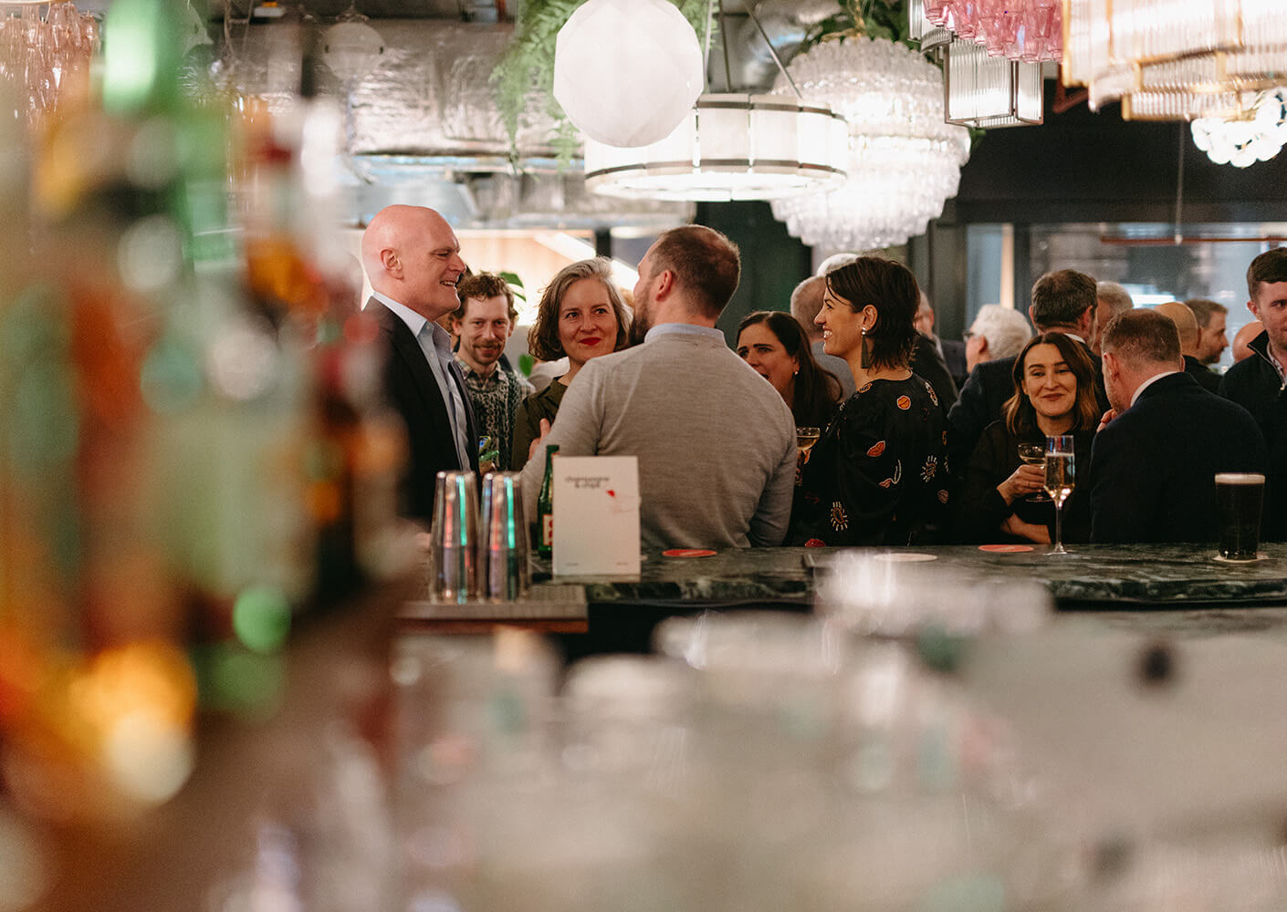 Group of people networking at a lively bar event with drinks and conversation.