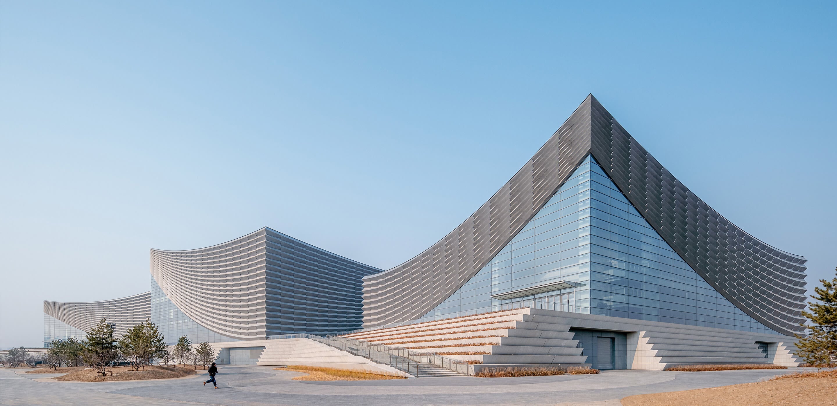 Modern architectural building in three volumes with a curved, glass facade.