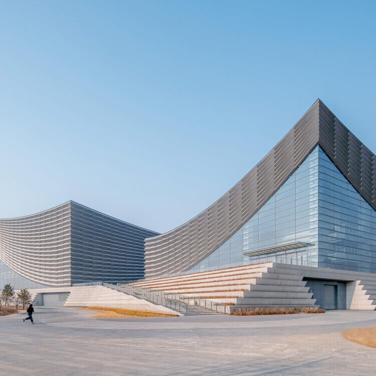 Modern architectural building in three volumes with a curved, glass facade.