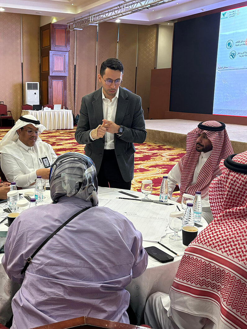 Business meeting with people in formal attire, discussing documents at a conference table.